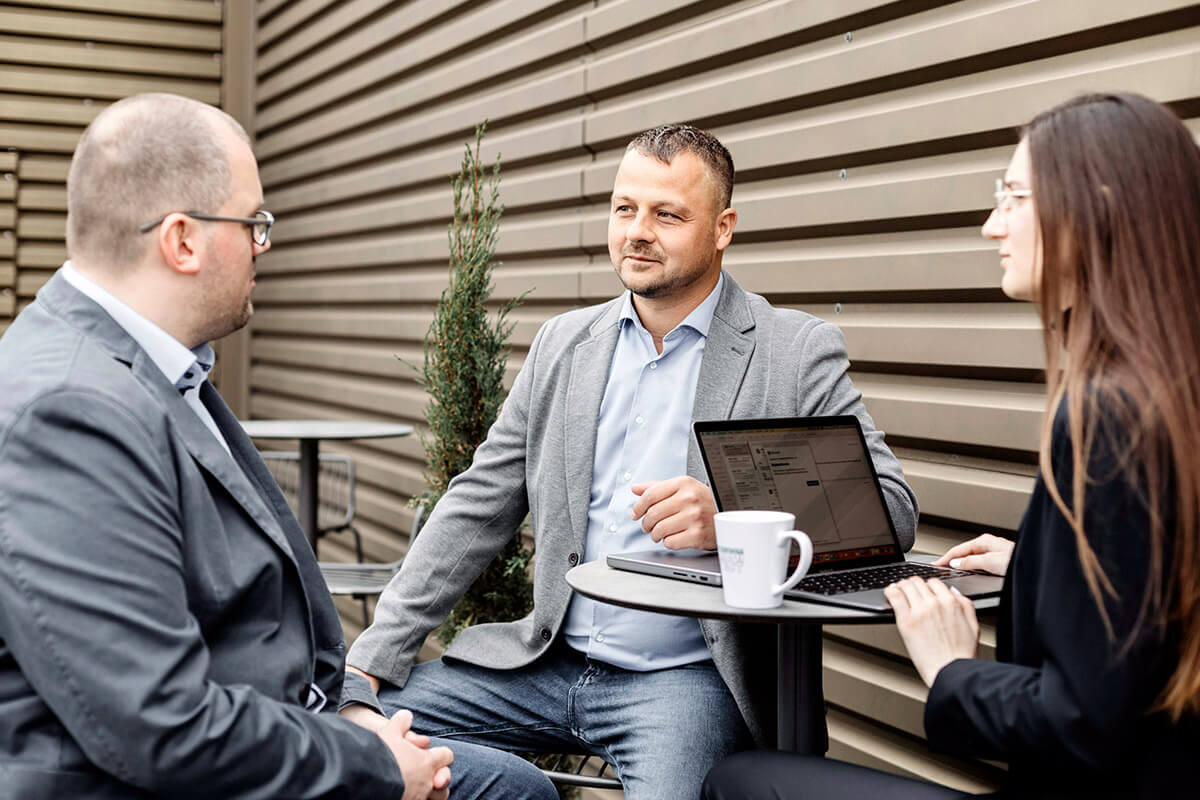 Bdat. colleagues at an outdoor meeting with a laptop and coffee
