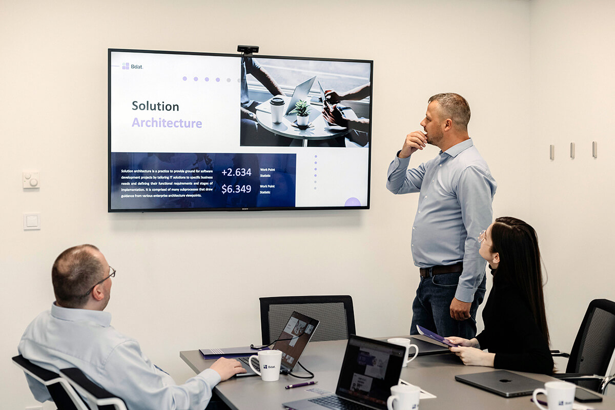 Team meeting in front of a Solution Architecture presentation slide